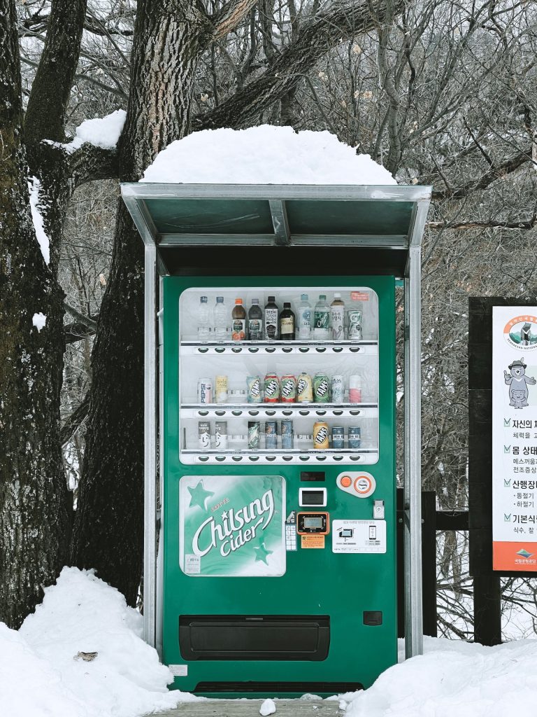 A green vending machine sitting in the snow